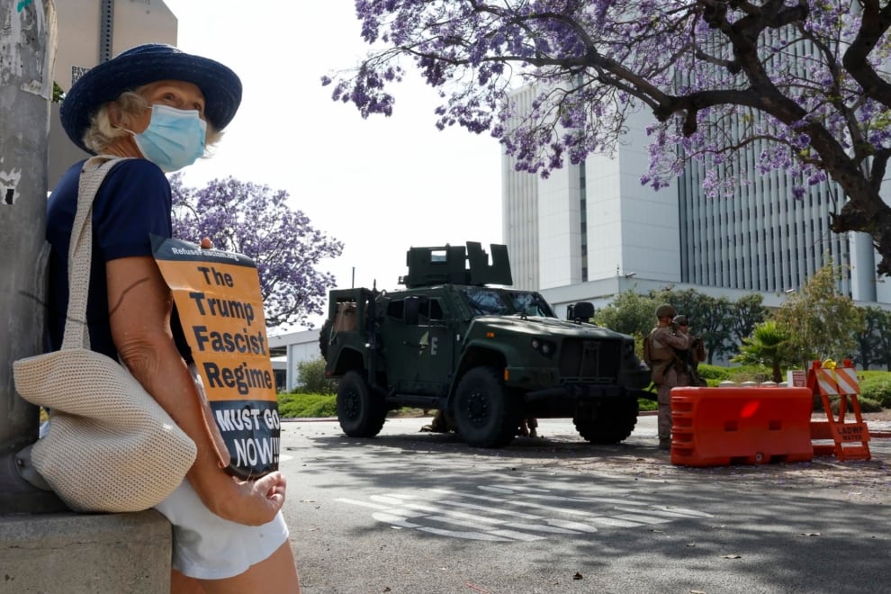 Un manifestant détient une bannière tandis que les Marines protègent un bâtiment fédéral à Los Angeles, en Californie. Efe / EPA / Caroline Brehman