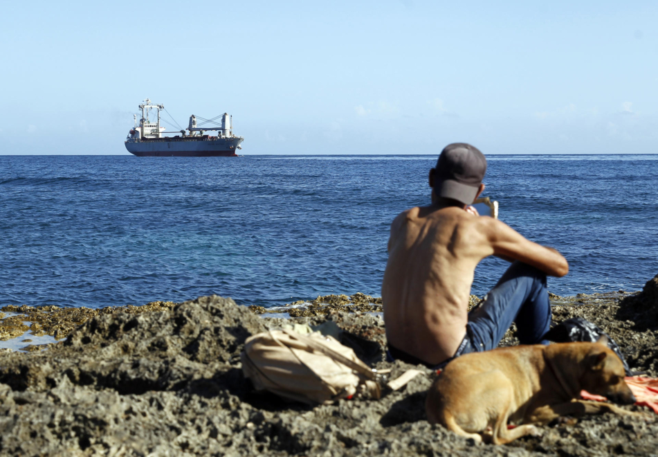 Un jeune homme observe l'arrivée d'un navire transportant de l'aide humanitaire au port de La Havane