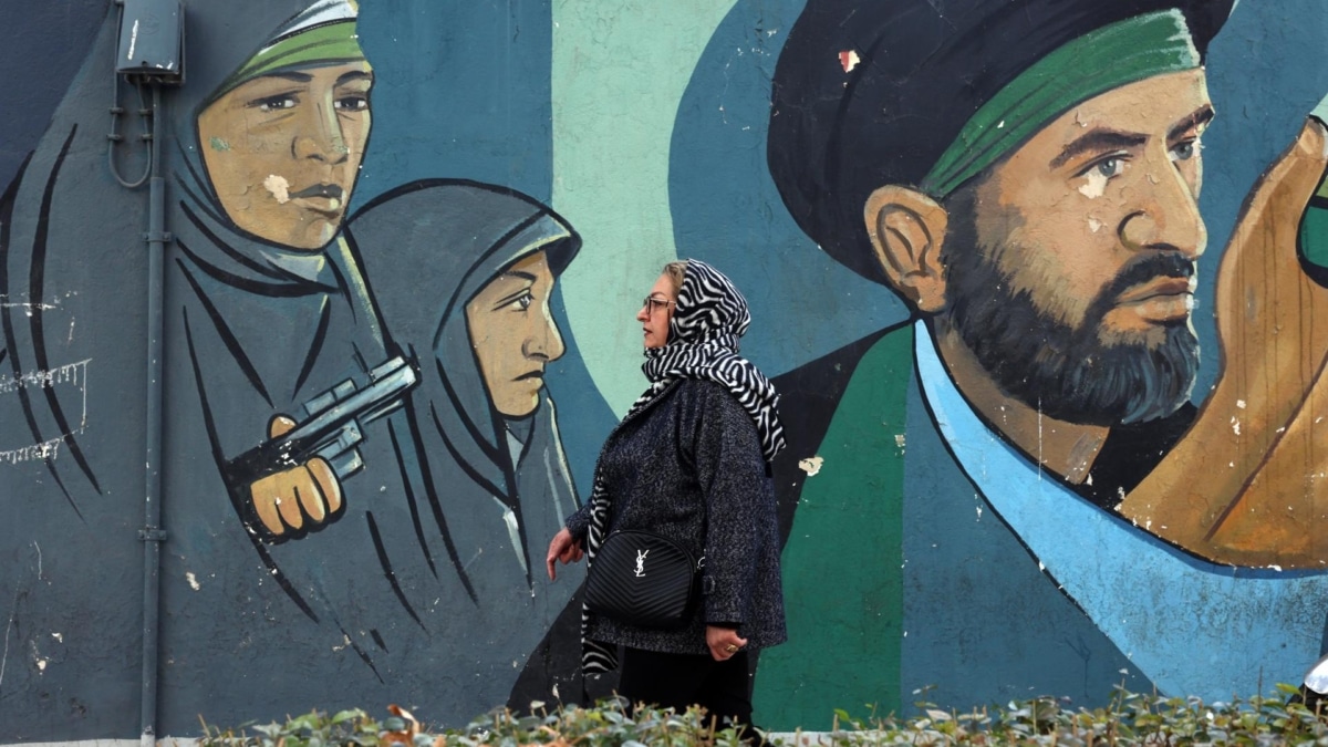 Una mujer pasea por Teherán cerca de un mural con soldados iraníes