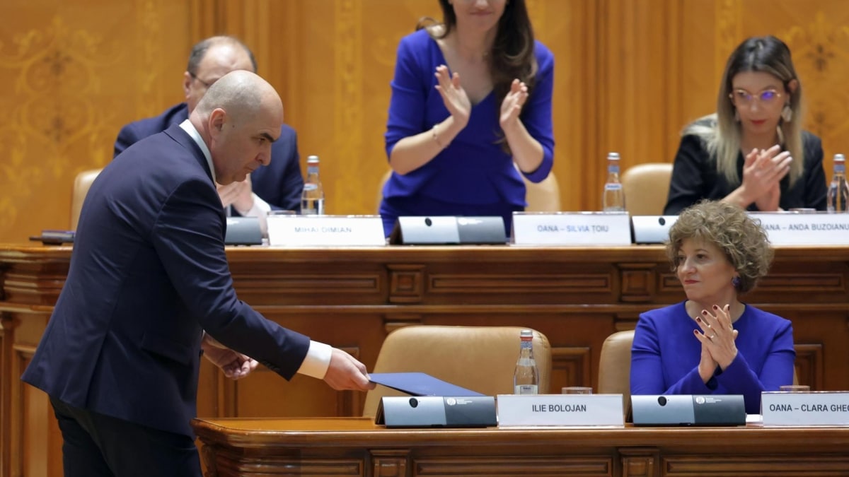 El primer ministro rumano, Ilie Bolojan, izda, recibe los aplausos de sus correligionarios antes de la moción de censura.