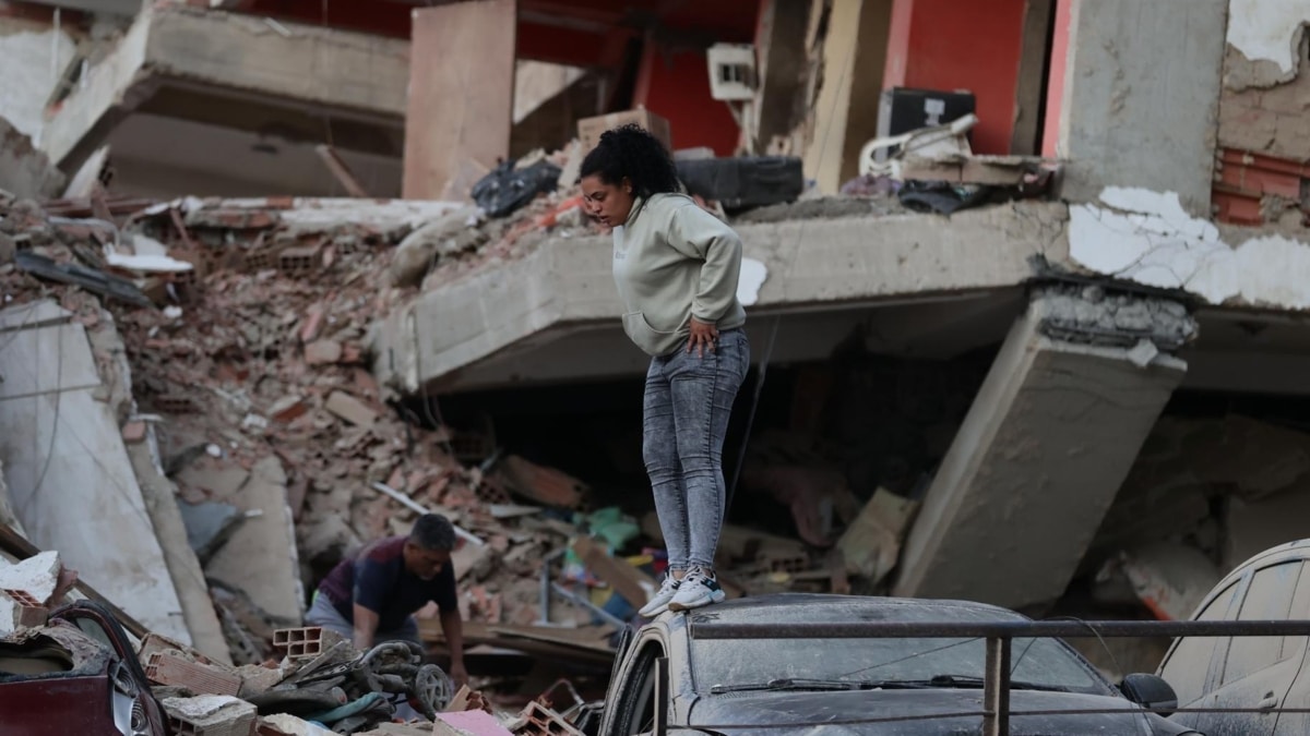 Residentes entre los escombros de un edificio en ruinas por los terremotos