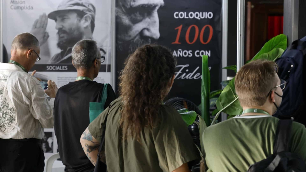 Varios asistentes al coloquio por el centenario de Castro observan libros y fotografías del líder cubano.